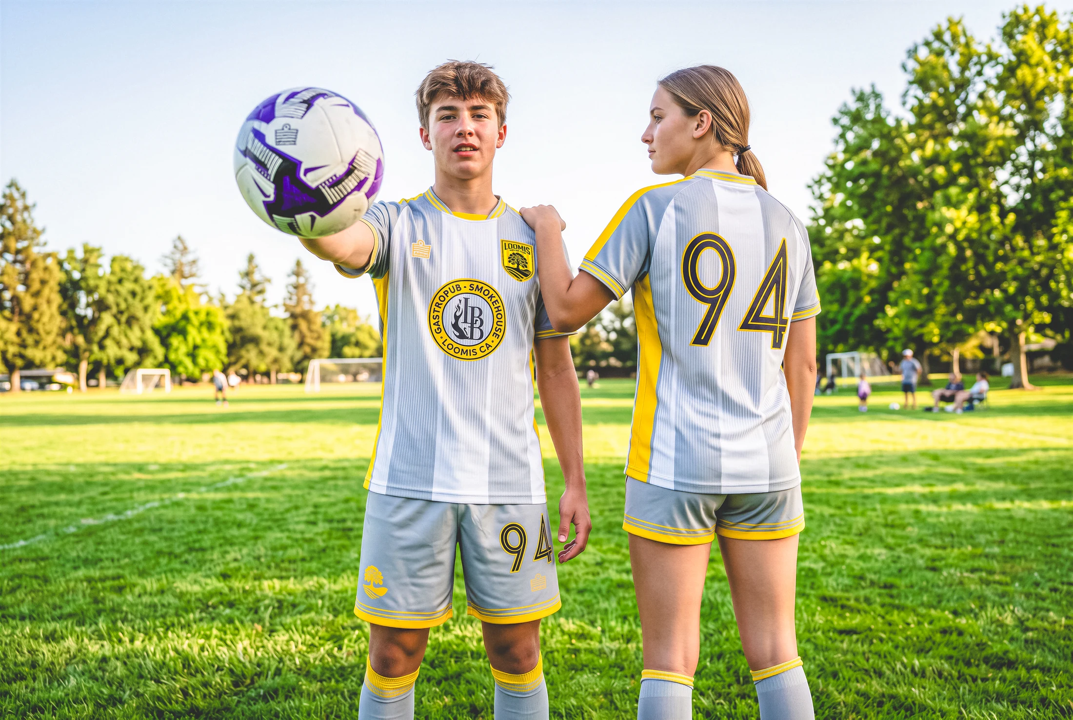 Two Loomis players on the field showing the front and back of the away kit